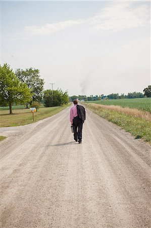 fifty year old man in a suit - Businessman walking away down a dirt road Stock Photo - Premium Royalty-Free, Code: 614-06336460