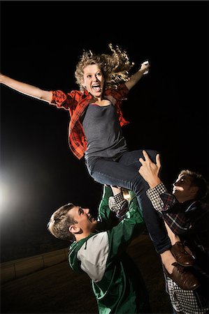 dark action - Two male friends lifting teenage girl, arms outstretched Stock Photo - Premium Royalty-Free, Code: 614-06402592