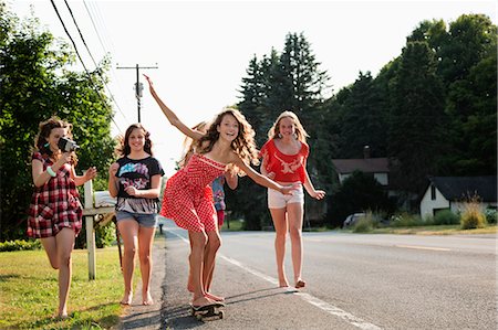 smiling teenage girl - Girl on skateboard with friends Stock Photo - Premium Royalty-Free, Code: 614-06402670