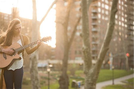 Jeune femme joue de la guitare dans le parc Photographie de stock - Premium Libres de Droits, Code: 614-06402731