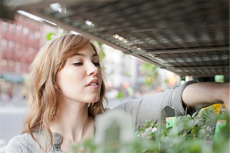 people at a market - Young woman choosing plants from stall Stock Photo - Premium Royalty-Free, Code: 614-06402774