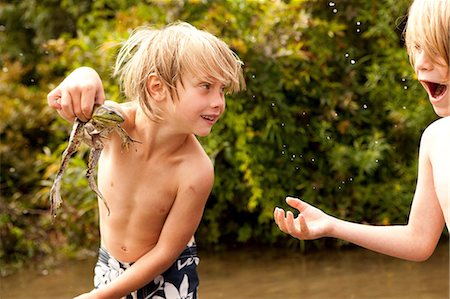 Boy holding frog up whilst friend looks on in amazement Stock Photo - Premium Royalty-Free, Code: 614-06402886