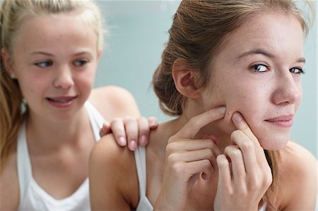 dirt in face with smile - Girl squeezing a spot, friend with hand on shoulder Stock Photo - Premium Royalty-Free, Code: 614-06403018