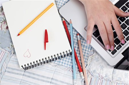 Teenage girl using laptop with notepad and pencils Stock Photo - Premium Royalty-Free, Code: 614-06403029