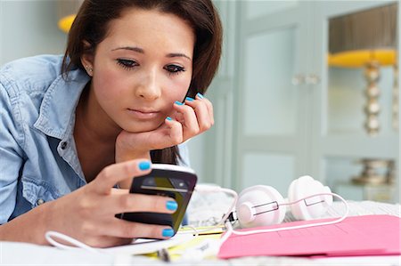 smartphone on bed - Teenage girl looking at cellphone Stock Photo - Premium Royalty-Free, Code: 614-06403020