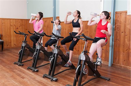 spinning class - Women on exercise bikes, drinking from bottles Stock Photo - Premium Royalty-Free, Code: 614-06442284