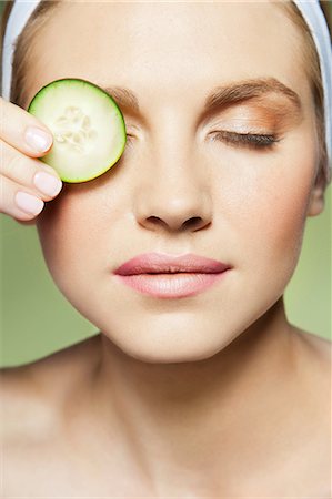 simsearch:614-06442320,k - Woman covering eye with piece of cucumber Stock Photo - Premium Royalty-Free, Code: 614-06442341