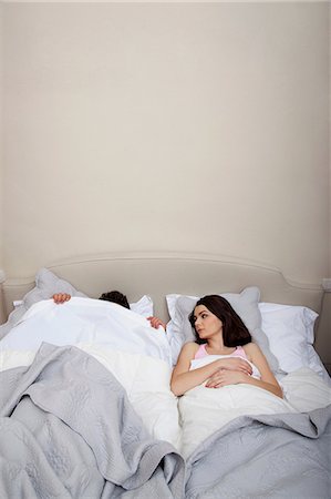 Couple in bed, man hiding under duvet Stock Photo - Premium Royalty-Free, Code: 614-06442394