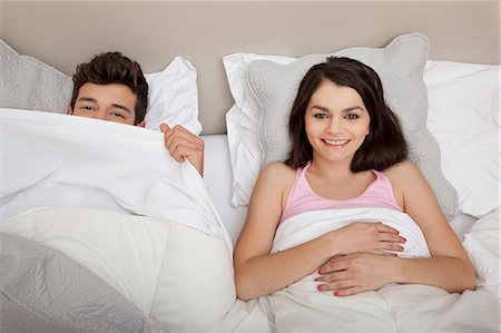 Couple in bed, man peeking behind duvet Foto de stock - Sin royalties Premium, Código: 614-06442396