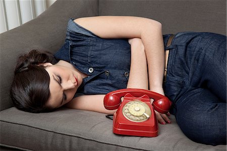 Woman lying on sofa with telephone Stock Photo - Premium Royalty-Free, Code: 614-06442439