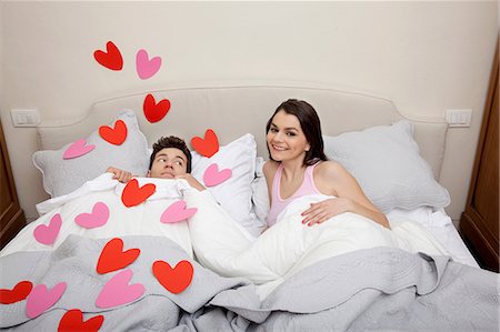 Couple in bed with heart shapes on bedclothes Stock Photo - Premium Royalty-Free, Code: 614-06442441