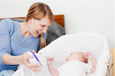 Mother smiling at newborn daughter in bassinet Stock Photo - Premium Royalty-Free, Code: 614-06442540