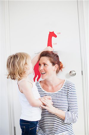 door female - Daughter measuring mother on height chart Stock Photo - Premium Royalty-Free, Code: 614-06442558