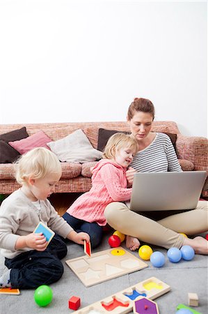 family playing candid - Mother using laptop, children playing Stock Photo - Premium Royalty-Free, Code: 614-06442562