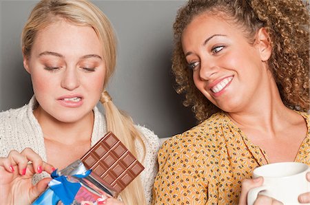 Woman staring at friend holding chocolate Fotografie stock - Premium Royalty-Free, Codice: 614-06442629