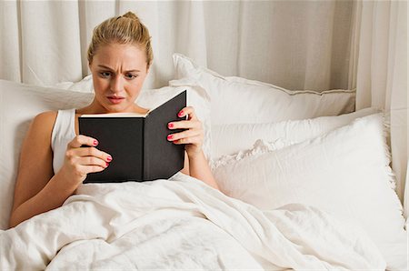 person reading a book confused - Livre de lecture de femme au lit Photographie de stock - Premium Libres de Droits, Code: 614-06442634