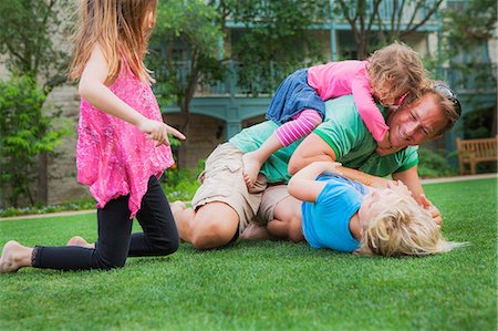 Father playing with his daughters in garden Stock Photo - Premium Royalty-Free, Code: 614-06442648
