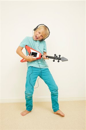 Boy wearing headphones playing guitar Stock Photo - Premium Royalty-Free, Code: 614-06442821