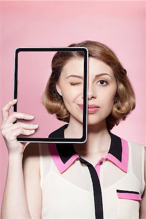 Woman covering half her face with digital tablet Stock Photo - Premium Royalty-Free, Code: 614-06442854