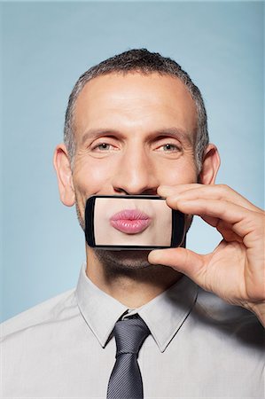 simsearch:614-06442853,k - Man covering mouth with smartphone Foto de stock - Sin royalties Premium, Código: 614-06442885