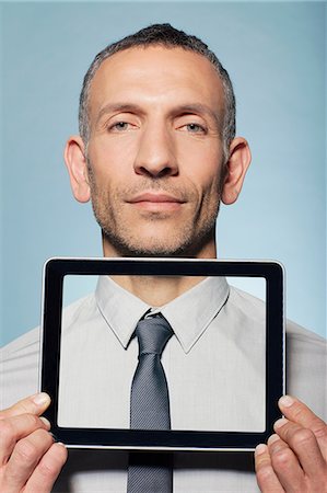 portrait of man holding computer - Man covering neck with digital tablet Stock Photo - Premium Royalty-Free, Code: 614-06442883