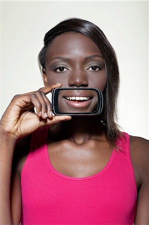 Teenage girl holding smartphone over mouth Foto de stock - Sin royalties Premium, Código: 614-06442912