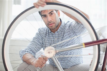 Man fixing bicycle wheel indoors Photographie de stock - Premium Libres de Droits, Code: 614-06536764