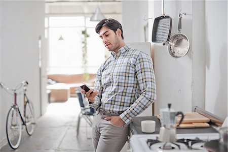electronics photos - Man using cell phone in kitchen Stock Photo - Premium Royalty-Free, Code: 614-06536776