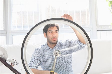 Man fixing bicycle wheel indoors Photographie de stock - Premium Libres de Droits, Code: 614-06536771