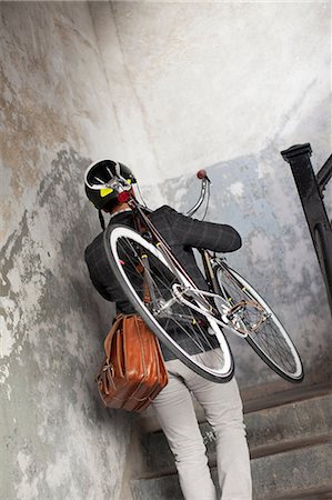 Man carrying bicycle up staircase Stock Photo - Premium Royalty-Free, Code: 614-06536788