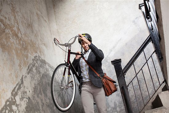 Man carrying bicycle down staircase Stock Photo - Premium Royalty-Free, Image code: 614-06536789