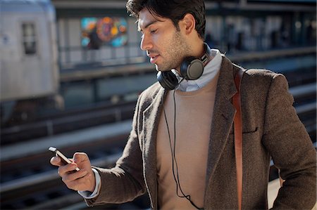 Man using cell phone at train station Stock Photo - Premium Royalty-Free, Code: 614-06536798