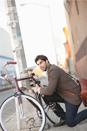 portrait of a young man - Man locking bicycle on city street Stock Photo - Premium Royalty-Free, Code: 614-06536829