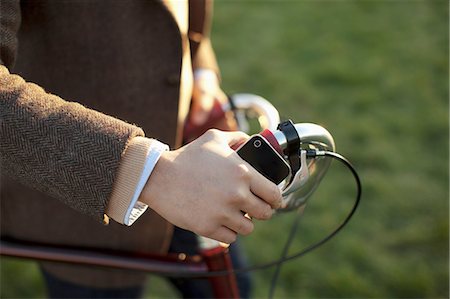 Man with cell phone pushing bicycle Photographie de stock - Premium Libres de Droits, Code: 614-06536820