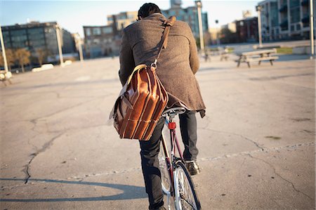 rear view of a boy - Man riding bicycle on city street Stock Photo - Premium Royalty-Free, Code: 614-06536822