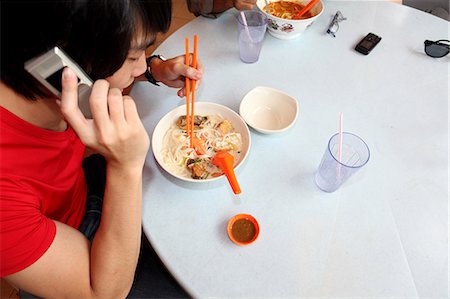 electronic devices for communication - Man talking on cellphone and eating Stock Photo - Premium Royalty-Free, Code: 614-06536909