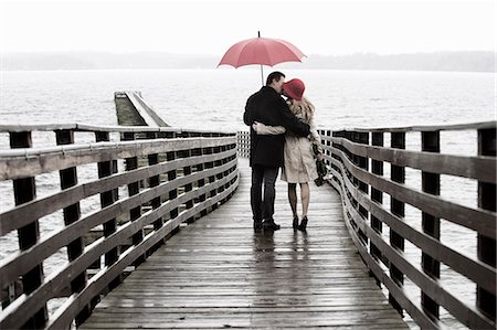 rainy hug with girlfriend images - Couple kissing on wooden pier in rain Stock Photo - Premium Royalty-Free, Code: 614-06536901