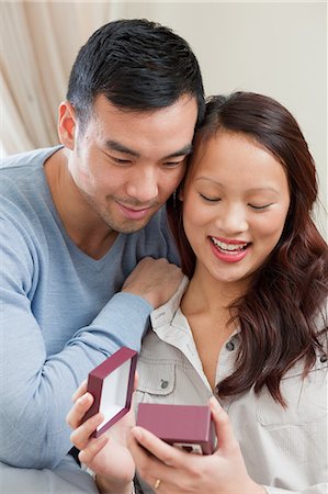 romantic young couple - Man giving girlfriend gift on sofa Stock Photo - Premium Royalty-Free, Code: 614-06536932