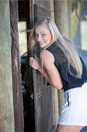 Smiling woman opening door Stock Photo - Premium Royalty-Free, Code: 614-06536969