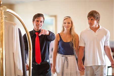 Porter talking to couple in hotel lobby Stock Photo - Premium Royalty-Free, Code: 614-06537186