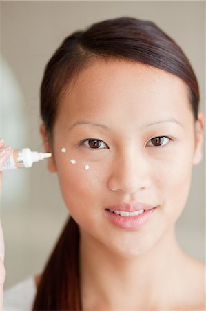 Woman applying moisturizer in bathroom Foto de stock - Royalty Free Premium, Número: 614-06537536