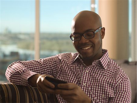 Man using cell phone on sofa Photographie de stock - Premium Libres de Droits, Code: 614-06624238