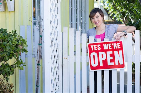 Woman hanging open sign on fence Stock Photo - Premium Royalty-Free, Code: 614-06624448