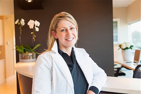 doctor office happy - Doctor smiling at receptionist's desk Stock Photo - Premium Royalty-Free, Code: 614-06624821