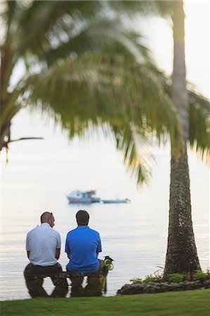 simsearch:614-06624865,k - Men sitting under palm tree on beach Foto de stock - Sin royalties Premium, Código: 614-06624852