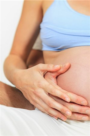 pregnant woman holding her stomach - Couple holding woman's pregnant belly Stock Photo - Premium Royalty-Free, Code: 614-06624909