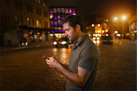 people outside at night - Man using cell phone on city street Foto de stock - Sin royalties Premium, Código: 614-06625023