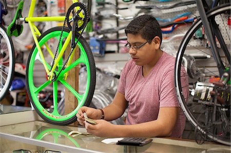 eyeglasses teenager boy - Mechanic counting till in bicycle shop Stock Photo - Premium Royalty-Free, Code: 614-06625227