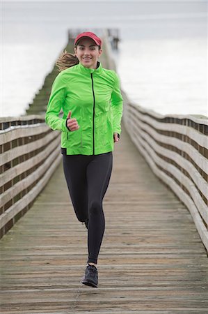 front view - Woman running on wooden dock Stock Photo - Premium Royalty-Free, Code: 614-06625320