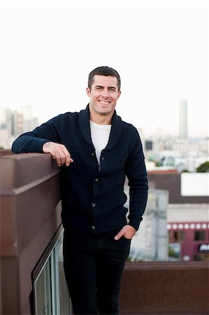 single man standing - Smiling man standing on urban balcony Stock Photo - Premium Royalty-Free, Code: 614-06625399